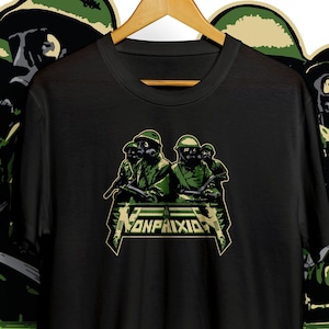Puede incluir: Camiseta negra con un gráfico verde de soldados con máscaras de gas y cascos, sosteniendo rifles. La palabra "NONPAIXID" está impresa en una fuente estilizada en el pecho. El diseño tiene un tema militar.