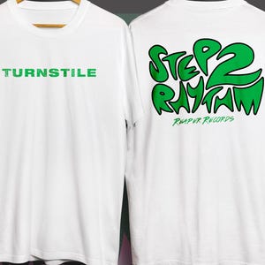 Può includere: T-shirt bianche con testo verde. La parte anteriore della maglietta dice "TURNSTILE" in un carattere verde strutturato. La parte posteriore della maglietta dice "STEP 2 RHYTHM" in un carattere verde a bolle, con "REAPER RECORDS" sotto.