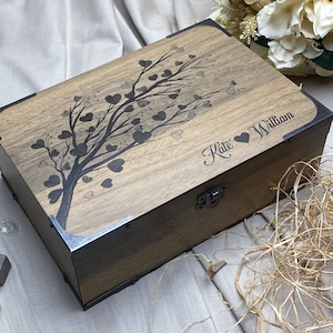 Artisan-crafted rectangular wooden box with natural wood color. Vintage-style L-shaped metal brackets adorn corners. Front lid features heart-shaped leaf tree design, adding rustic charm and artistic appeal