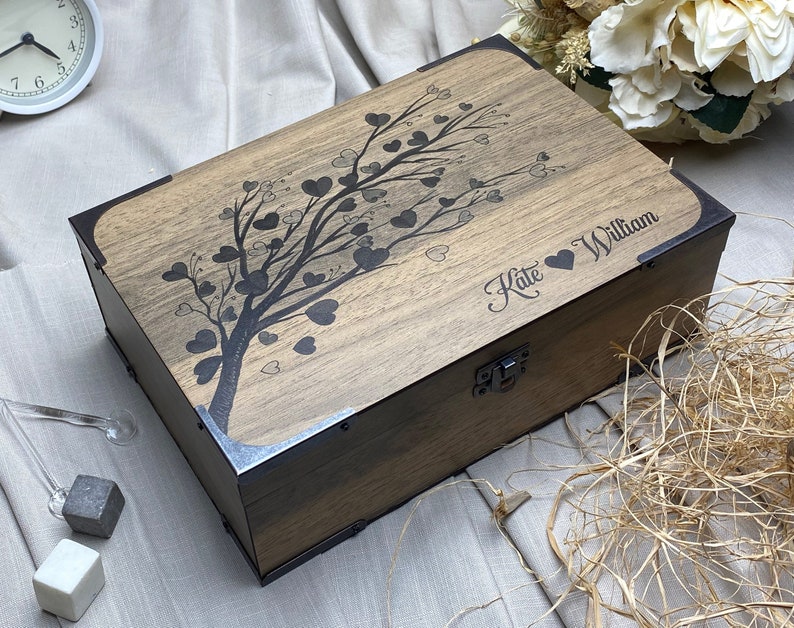 Artisan-crafted rectangular wooden box with natural wood color. Vintage-style L-shaped metal brackets adorn corners. Front lid features heart-shaped leaf tree design, adding rustic charm and artistic appeal