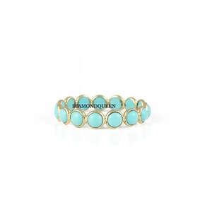 May include: A gold band ring with a row of turquoise blue stones.