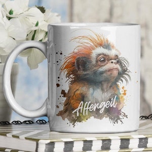 Könnte beinhalten: Weiße Keramiktasse mit einer Aquarell-Illustration eines Affen mit rotem Fell und weißem Gesicht. Die Tasse hat den Text "Affen geil" aufgedruckt.