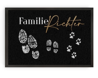 May include: Black doormat with the text "Familie Richter" in white and gold lettering. The doormat features white footprints and paw prints.