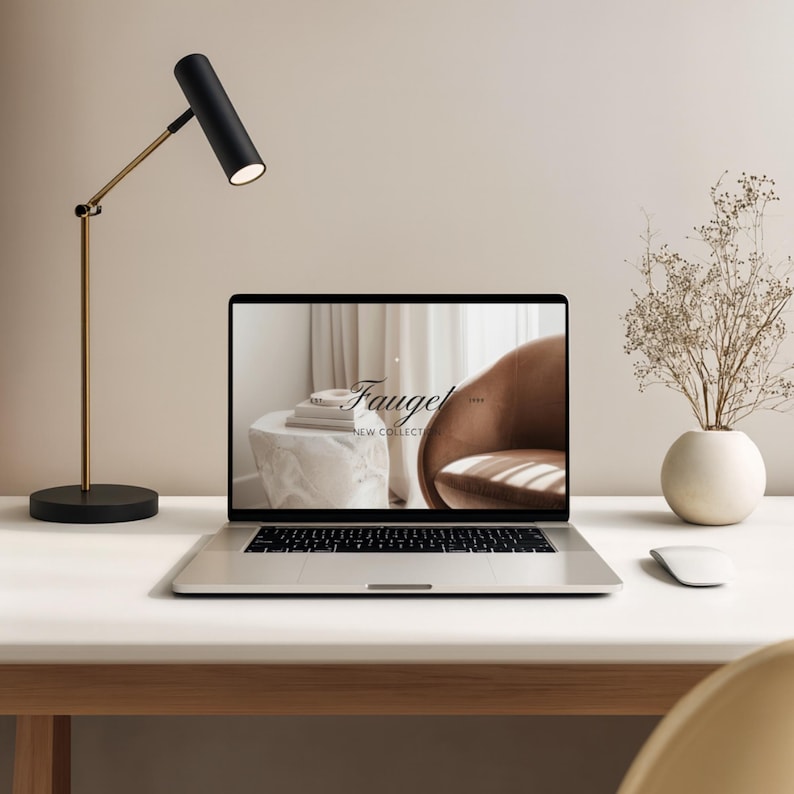 May include: A modern desk setup featuring a laptop displaying the "Fauget New Collection" logo. A black and gold desk lamp illuminates the scene, alongside a white mouse and a vase with dried flowers. The desk is white.