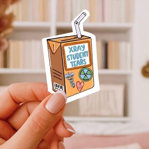 May include: A sticker in the shape of a juice box with the text "XRAY STUDENT TEARS". The sticker is orange with a white straw and features medical-themed graphics, including a caduceus and a heart.