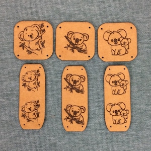 Puede incluir: Siete recortes de madera de koala con diferentes poses. Los recortes son marrones y tienen un acabado de madera natural.