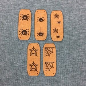 Könnte beinhalten: Sechs braune rechteckige Holzetiketten mit schwarzen Spinnen- und Spinnennetz-Designs. Die Etiketten sind perfekt, um Ihren Halloween-Bastelarbeiten eine gruselige Note zu verleihen.