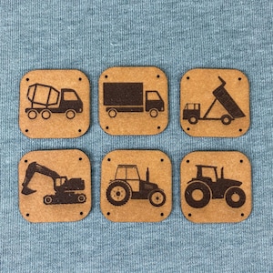 Può includere: Sei quadrati di legno con diversi veicoli da costruzione stampati su di essi. I veicoli includono una betoniera, un camion con pianale, un camion ribaltabile, un escavatore e due trattori.