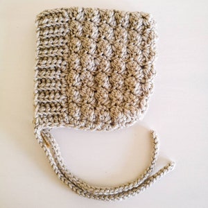 Peut inclure: Un bonnet de bébé en crochet beige avec un nœud noué en bas.