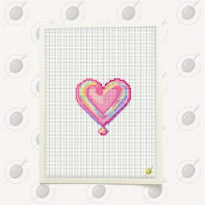 May include: A cross-stitch heart design in shades of pink, yellow, and blue, with a small, round accent at the bottom. The heart is centered on a white canvas with a cream-colored border. The background is a repeating pattern of a needle and thread.