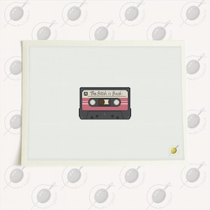 Könnte beinhalten: Ein Kreuzstichmuster mit einer Retro-Kassette mit rosa Etikett und dem Text The Bitch is Back in schwarzer Schreibschrift. Das Design ist auf einem weißen Rasterhintergrund zentriert und zeigt eine detaillierte Handarbeitsdarstellung.