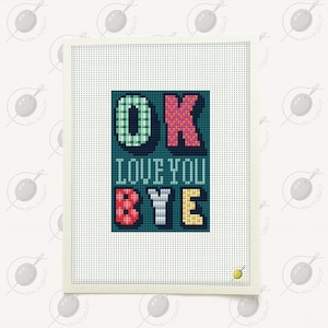 May include: A cross-stitch artwork with the words "OK LOVE YOU BYE" in colorful letters on a teal background. The letters are in various colors, including green, pink, red, white, and yellow. The artwork is framed in a white border.