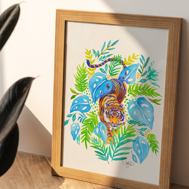 Puede incluir: Pintura acuarela de un tigre caminando por una escena de jungla. El tigre es naranja y negro con rayas azules. La jungla est&aacute; llena de hojas verdes y flores azules. La pintura est&aacute; enmarcada en un marco de madera claro.