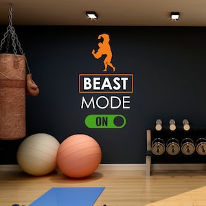 May include: A black wall with a motivational quote that says "BEAST MODE ON" with a green and white toggle switch. There is a silhouette of a muscular man in an orange color. There is a punching bag, two exercise balls, and a weight rack with dumbbells in the image.