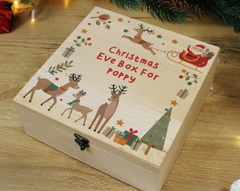 May include: A light-colored wooden Christmas Eve box with a hinged lid. The box is decorated with reindeer, a Christmas tree, and Santa Claus in a sleigh. The text "Christmas Eve Box For Poppy" is printed on the lid.