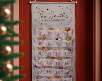 May include: A gray fabric Christmas advent calendar with 24 numbered pockets. The text "The Smith's Christmas Countdown" is printed at the top. The pockets are filled with small gifts and candies. A white string is used for hanging.