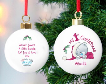 May include: Two white Christmas baubles with red ribbons and gold caps. One features text: "Archie James, A little Bundle Of joy & love." The other says "My 1st Christmas" with a teddy bear graphic and the name "Archie".