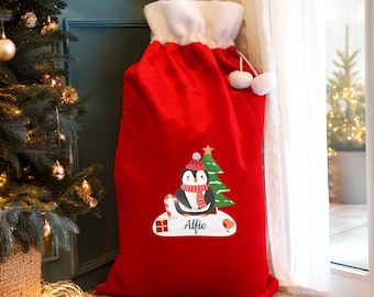 May include: A large red Christmas gift sack with a white fluffy top and drawstring closure. The sack features a cartoon penguin wearing a hat and scarf, a Christmas tree, and the name "Alfie".