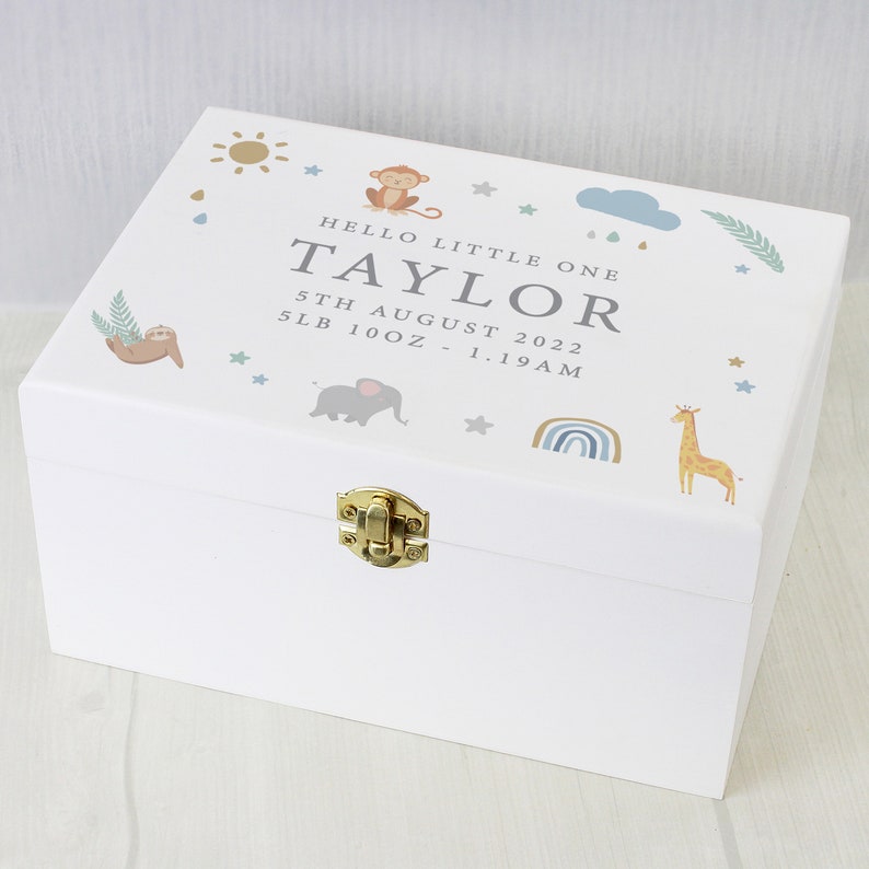 May include: A white wooden keepsake box with a gold clasp, decorated with jungle animal illustrations and the text "HELLO LITTLE ONE TAYLOR 5th AUGUST 2022 5LB 10OZ - 1.19AM". The box features a sun, monkey, sloth, elephant, rainbow, and giraffe.