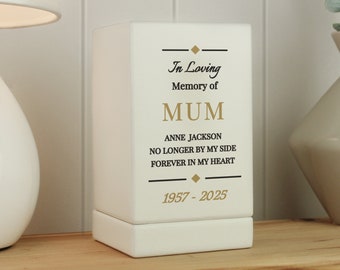 May include: White ceramic box with a black border and gold lettering. The text reads "In Loving Memory of MUM ANNE JACKSON NO LONGER BY MY SIDE FOREVER IN MY HEART 1957-2025".