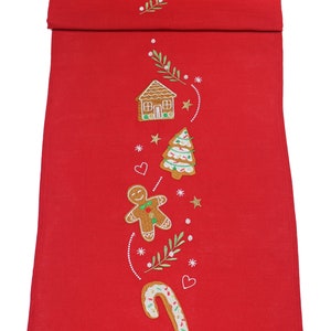 Puede incluir: Camino de mesa navideño rojo con diseños bordados de casa de jengibre, árbol, hombre y bastón de caramelo. El camino de mesa presenta líneas punteadas blancas, estrellas y ramitas de vegetación. Una decoración festiva.