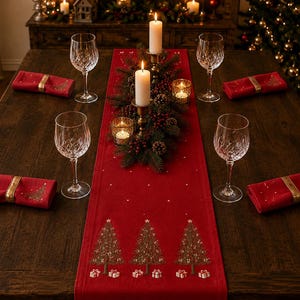 Pode incluir: Um caminho de mesa vermelho com árvores de Natal castanhas bordadas e presentes brancos, sobre uma mesa de madeira com quatro copos de vinho de cristal, guardanapos vermelhos com anéis dourados e um centro de velas e ramos.