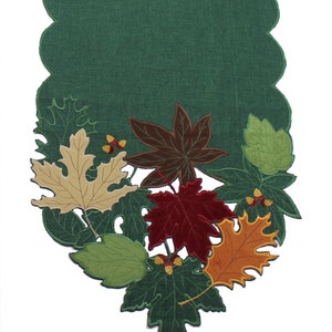 May include: A green table runner with a scalloped edge and embroidered autumn leaves in shades of brown, red, orange, and green.