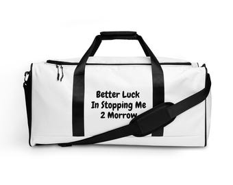 May include: White duffel bag with black handles, shoulder strap, and zipper pulls. The bag features the text "Better Luck In Stopping Me 2 Morrow" in black, centered on the front. The bag is designed for carrying sports gear or travel items.
