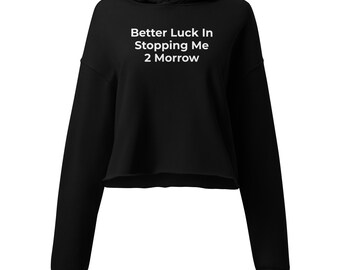 May include: A black cropped hoodie featuring long sleeves, a hood, and white text printed on the chest that reads Better Luck In Stopping Me 2 Morrow. The garment has a raw-edge hemline and a standard fit, showcasing a simple and clean design.