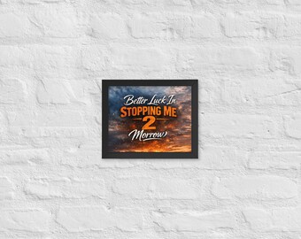 May include: A framed print with the text "Better Luck In Stopping Me 2 Morrow" in white and orange lettering. The background of the print is a cloudy sky with orange and blue hues.