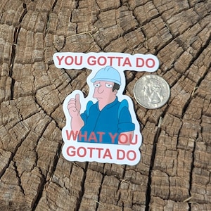 May include: A sticker featuring a cartoon character in a blue uniform and hard hat, giving a thumbs up. The sticker has the text "YOU GOTTA DO WHAT YOU GOTTA DO" in red and white. A quarter is next to the sticker.