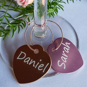 May include: Two gold heart-shaped wine glass charms with the names "Daniel" and "Sarah" engraved on them.