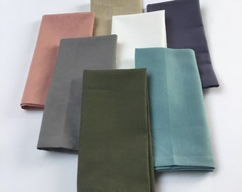 May include: Set of eight folded fabric napkins in various colors, including beige, pink, gray, green, white, and blue.
