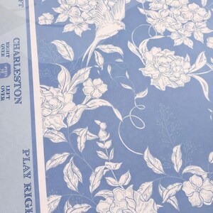 Puede incluir: Tela azul claro con estampado floral con flores blancas, hojas y un dise&ntilde;o de p&aacute;jaro. Los textos "CHARLESTON" y "PLAY RIGHT" son visibles. La tela tiene una est&eacute;tica vintage.
