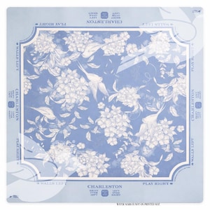 May include: A square, light blue mat with a floral and bird pattern. The design features white flowers and birds on a blue background. The words "Charleston" and "Walls Left" are printed on the mat.