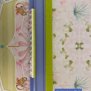 May include: A blue Mahjong tile rack with green tiles and a row of patterned tiles. The text on the image reads: "tile sizes shown .87w X .75D X 1.25"Tall". The background features a whimsical pattern with monkeys and floral designs.