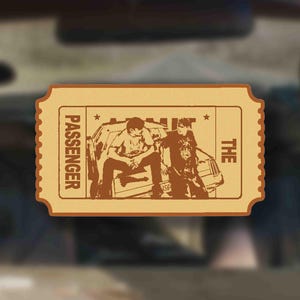Puede incluir: Boleto beige con las palabras "THE PASSENGER" y una ilustración de dos personas en un coche. El boleto tiene un borde festoneado, sobre un fondo borroso de interior de coche.