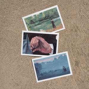 May include: Three rectangular art prints featuring painted scenes. The top print shows a figure near a river and cabin. The middle print depicts a close-up of two hands touching. The bottom print displays a figure in a misty, blue-toned landscape.