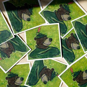 May include: A collection of vintage illustrations featuring a cartoon bear wearing a green hat and a green outfit. The illustrations are printed on white paper and have a green background.