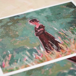 May include: Art print showing a watercolour painting of a person in a dark dress in a field of tall grass. The artwork has a soft, dreamy quality with greens, browns, and pinks. The print is on white paper.