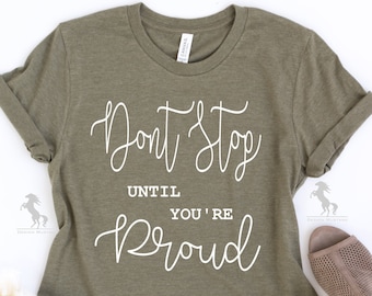 May include: A green t-shirt with the text "Don't Stop Until You're Proud" in white cursive lettering.