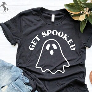 K&ouml;nnte beinhalten: Schwarzes T-Shirt mit einem wei&szlig;en Geistermotiv und dem Text "Get Spooked" in einer Retro-Schrift.
