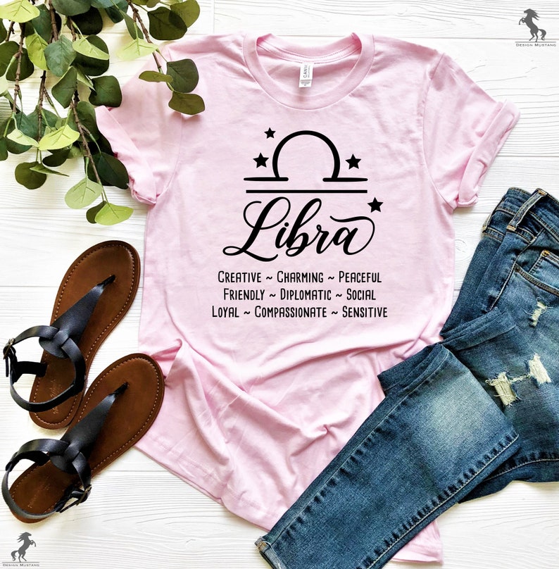 Pu&ograve; includere: Maglietta rosa con un segno zodiacale Bilancia nero e le parole "Creative ~ Charming ~ Peaceful ~ Friendly ~ Diplomatic ~ Social ~ Loyal ~ Compassionate ~ Sensitive".