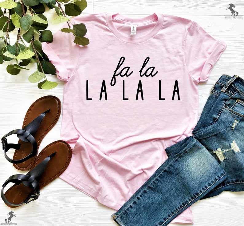 May include: A pink t-shirt with the text "fa la LA LA LA" printed in black.