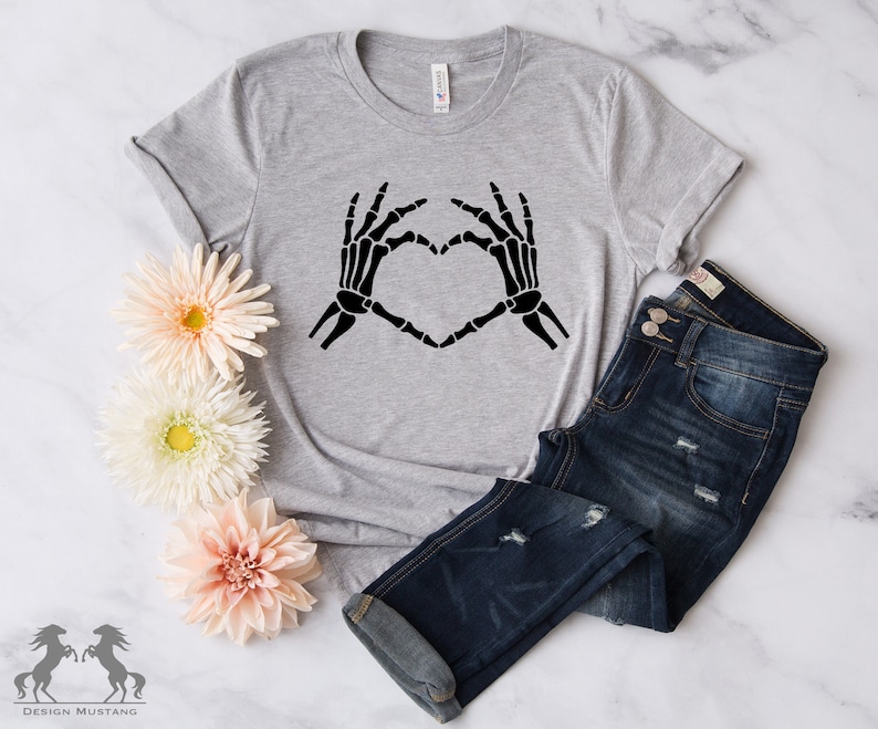 May include: A gray t-shirt with a black skeleton hand design making a heart shape.