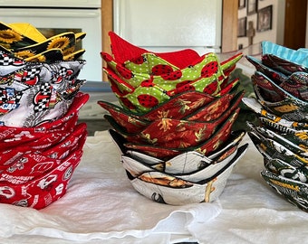 May include: A stack of 10 colorful fabric bowls with different patterns. The bowls are folded and stacked in three groups. The bowls are made of fabric and have a quilted design.