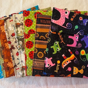 May include: A collection of fabric pouches with various patterns. Designs include patriotic themes, dogs, leaves, ladybugs, sunflowers, and cats. The cat pouch is black with pink, green, orange, and purple cat illustrations and the word "kitty".