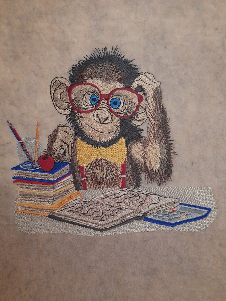 May include: Embroidered image of a monkey wearing red glasses, a yellow bow tie, and suspenders. The monkey is sitting at a desk with books, pencils, and an apple. A calculator and open book are also on the desk.