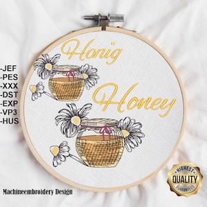 May include: Machine embroidery design for a honey jar with daisies and the words "Honig Honey" in yellow thread on a white background.