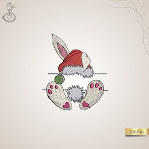 Könnte beinhalten: Gesticktes Design mit einem Hasen, der einen Weihnachtsmannhut trägt, mit sichtbarem flauschigem Schwanz und Füßen. Die Füße haben rosa herzförmige Polster. Eine grüne Kugel hängt unter dem Hut. Das Wort "DIGITAL" steht in einem goldenen Rechteck.